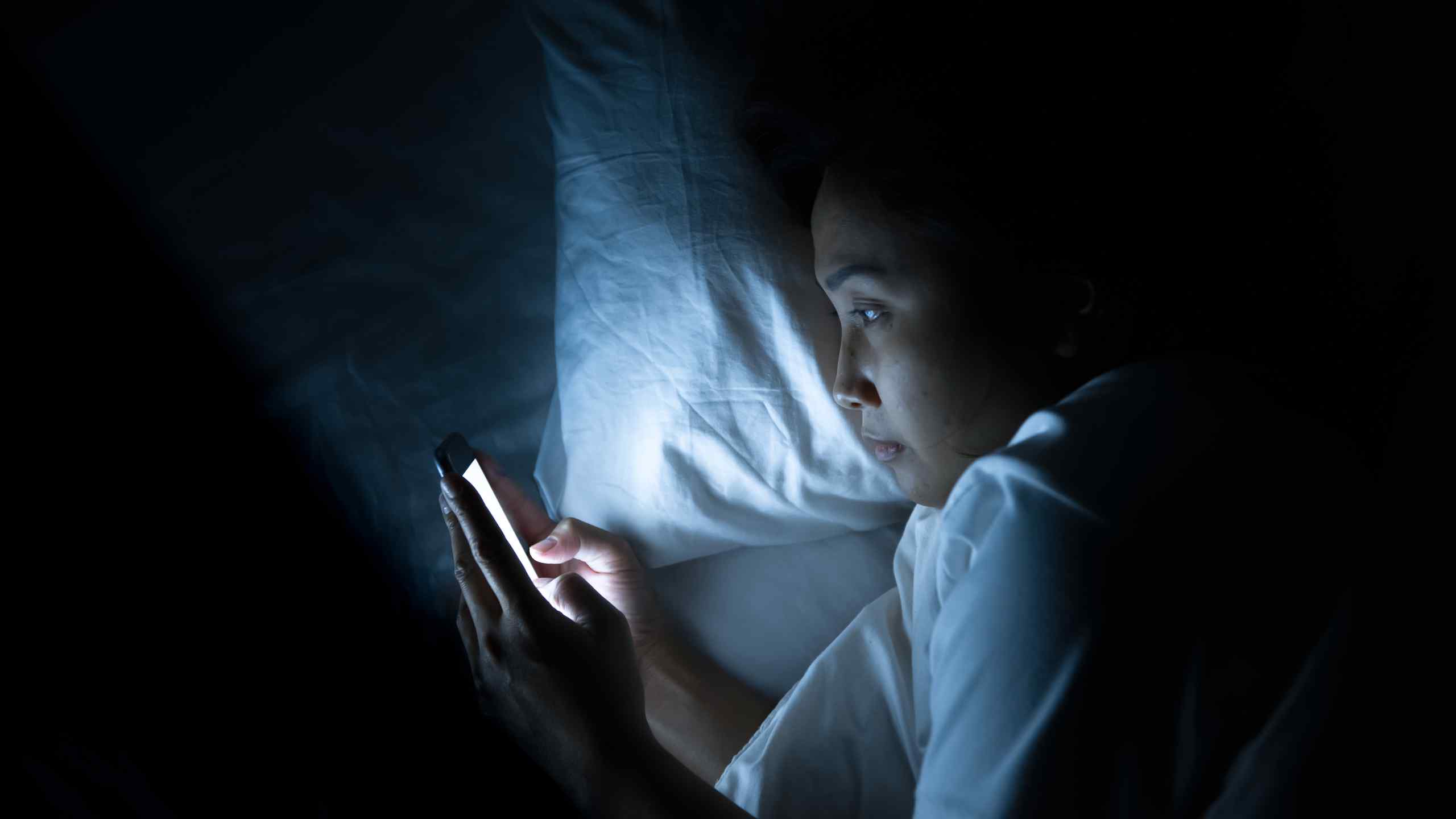 A woman using her smartphone in bed.